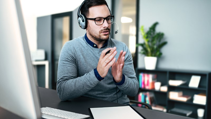 Man med headset i samtal framför dator.